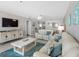 Living room features comfortable couches, ocean art, tiled floors, and access to dining area and television at 13500 Gulf Blvd # 506, Madeira Beach, FL 33708