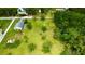 Drone shot displaying a spacious lot featuring scattered trees, a single-story home, shed, and a lush green lawn at 14318 Guava St, Hudson, FL 34667