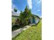 Exterior of a single-story house with a blue front door surrounded by trees and lush greenery under a partly cloudy sky at 14318 Guava St, Hudson, FL 34667