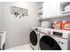 Well-organized laundry room with modern washer and dryer, storage cabinets, and decorative wall art at 15561 Stone House Dr, Brooksville, FL 34604