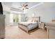 Bright main bedroom featuring a tray ceiling, a large window, and neutral-toned decor at 15561 Stone House Dr, Brooksville, FL 34604