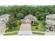 Aerial view of a well-maintained home with a three-car garage, driveway, and lush landscaping at 19312 Sunset Bay Dr, Land O Lakes, FL 34638