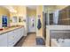 Bright bathroom featuring double vanities with granite countertops, a walk-in closet, and a shower with a tub at 19312 Sunset Bay Dr, Land O Lakes, FL 34638