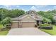 Attractive home with a three-car garage, brick-paved driveway, and mature palm trees at 19312 Sunset Bay Dr, Land O Lakes, FL 34638