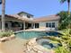 Tropical backyard with a pool and spa featuring rock accents, sandy beach, and mature landscaping at 2041 Gold Dust Ct, Trinity, FL 34655