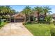 Charming home exterior with lush lawn, mature palms, stone accents, and three-car garage at 2041 Gold Dust Ct, Trinity, FL 34655