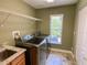 Laundry room with modern stainless steel washer and dryer, sink, wood cabinets and a window for natural light at 2041 Gold Dust Ct, Trinity, FL 34655