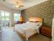 Bedroom featuring stone accent wall, ceiling fan, king bed, and view to exterior patio at 2041 Gold Dust Ct, Trinity, FL 34655