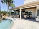 Outdoor kitchen with stone surround, a built-in grill, and a table for dining, located next to a sparkling pool at 2041 Gold Dust Ct, Trinity, FL 34655