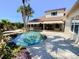 Beautiful backyard oasis featuring a sparkling pool, rock waterfall, lush landscaping, and a covered outdoor kitchen area at 2041 Gold Dust Ct, Trinity, FL 34655