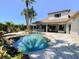 Backyard pool area with waterfall feature, lush landscaping, outdoor seating, and covered patio with bar at 2041 Gold Dust Ct, Trinity, FL 34655