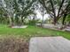 Spacious backyard with lush green grass, mature trees, a fire pit, and a wooden deck at 22443 Crows Nest Ct, Lutz, FL 33549