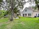 Exterior view of the home with a lush lawn, patio area, and mature trees at 22443 Crows Nest Ct, Lutz, FL 33549