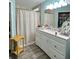 Bathroom featuring a white vanity with a marble countertop, decorative shower curtain, and a yellow accent table at 22443 Crows Nest Ct, Lutz, FL 33549