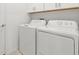 Modern laundry room with white washer and dryer and upper cabinets for storage at 22489 Storybook Cabin Way, Land O Lakes, FL 34637