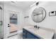 Modern bathroom featuring a sleek vanity, round mirror, and access door to the outdoor pool at 2306 S San Jose Cir, Tampa, FL 33629
