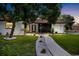 Charming home featuring a walkway lined with white stones, lush green lawn, and mature landscaping at 2306 S San Jose Cir, Tampa, FL 33629