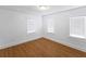 Bright bedroom features three windows with mini-blinds, white walls and trim, and wood floors at 2312 Highland S St, St Petersburg, FL 33705
