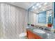 Bathroom with granite-topped vanity, decorative mirror, and shower with patterned curtain at 2630 Pearce Dr # 108, Clearwater, FL 33764