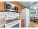 Kitchen with white appliances, wooden cabinets, stainless steel microwave and view to dining area at 2630 Pearce Dr # 108, Clearwater, FL 33764