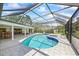Spacious screened-in pool area with a hot tub, lush landscaping, and an inviting backyard at 2900 Sandpiper Pl, Clearwater, FL 33762