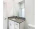 Bright bathroom with a granite vanity top, white cabinets, a large mirror, and modern fixtures at 31771 Blue Passing Loop, Wesley Chapel, FL 33545
