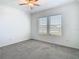 Neutral bedroom with a ceiling fan, carpeted floors, and natural light streaming through the windows at 31771 Blue Passing Loop, Wesley Chapel, FL 33545