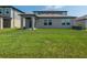 View of a home's backyard featuring a covered patio and a lush green lawn at 35100 Brackett Bnd, Zephyrhills, FL 33541