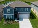 Two-story home features an attached two-car garage, beautiful blue siding, and landscaped front yard at 35100 Brackett Bnd, Zephyrhills, FL 33541