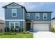 Charming two-story home features a two-car garage, attractive blue siding, and a lush green lawn at 35100 Brackett Bnd, Zephyrhills, FL 33541