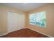 This bedroom has wood floors, a window with blinds, and a double-door closet at 37712 Aaralyn Rd, Zephyrhills, FL 33542