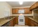 Functional kitchen featuring wooden cabinetry, granite countertops, and a complete set of appliances at 37712 Aaralyn Rd, Zephyrhills, FL 33542