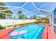 Enclosed pool with ample seating, red deck, and clear blue water offer a luxurious backyard oasis at 4360 82Nd N Ave, Pinellas Park, FL 33781