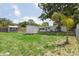 Expansive backyard with a storage shed and exterior view of the home, enclosed by fencing and mature trees at 4512 S Lois Ave, Tampa, FL 33611