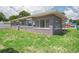 Grey brick home featuring a lush green backyard, windows, and mature trees at 4512 S Lois Ave, Tampa, FL 33611