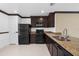 Open kitchen with black appliances, granite countertops, and tiled floors at 4831 Hillman Ter, North Port, FL 34288