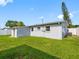 Backyard with grassy lawn and view of the back of the home with a small AC unit at 4925 Murray Hill Dr, Tampa, FL 33615
