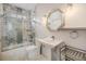 Well-lit bathroom featuring a tub with glass doors, marble tiles, a large mirror, and modern fixtures at 501 Knights Run Ave # 6104, Tampa, FL 33602