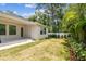 Spacious backyard with a covered patio and manicured lawn, bordered by tropical foliage and a privacy fence at 527 Bay St, Dunedin, FL 34698