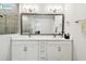 Bright bathroom with double sinks, white cabinets, modern lighting, framed mirror and updated tile shower at 527 Bay St, Dunedin, FL 34698