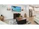 Bright living room with a large TV, a stylish rug, and an open view into the kitchen at 527 Bay St, Dunedin, FL 34698