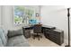 An office is furnished with a gray sofa, a desk, and a lamp, enhanced by natural light from the window at 527 Bay St, Dunedin, FL 34698