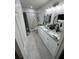 Bright bathroom featuring dual sinks, granite countertops, and a walk-in shower with white marble-look tile at 601 N Hercules Ave # 1008, Clearwater, FL 33765