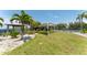 A grassy lawn leads to shade canopies and tennis courts in a tropical setting at 611 Destiny Dr # 509, Ruskin, FL 33570