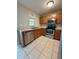 View of kitchen with stainless steel appliances, sink and tan tile flooring at 6333 Maisie Rd, Zephyrhills, FL 33542