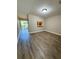 Living space features wood-look flooring, neutral walls, and a view into the kitchen, as well as a sliding glass door to the outside at 6333 Maisie Rd, Zephyrhills, FL 33542