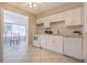 Well-lit kitchen featuring white cabinetry and tile flooring, with a breakfast area viewable through an opening at 6702 49Th N Ave, St Petersburg, FL 33709
