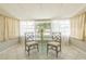 Sunroom with a glass table set for dining, surrounded by windows and light-filtering curtains at 6702 49Th N Ave, St Petersburg, FL 33709