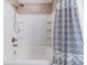 A well-lit bathtub and shower featuring white tile walls and stylish black and white shower curtain at 6736 Breezy Palm Dr, Riverview, FL 33578