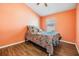 Bright bedroom featuring orange walls, a wood floor, and a colorful patterned bedspread at 6736 Breezy Palm Dr, Riverview, FL 33578
